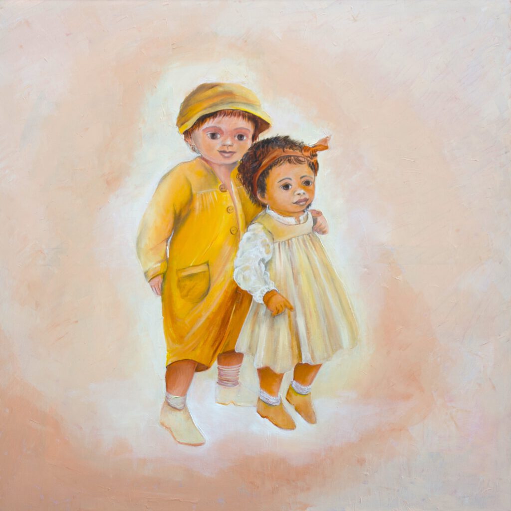 Twee kleuters in beige tinten, het jongetje met pet slaat armpje om meisje heen, meisje draagt haarband en jurkje.